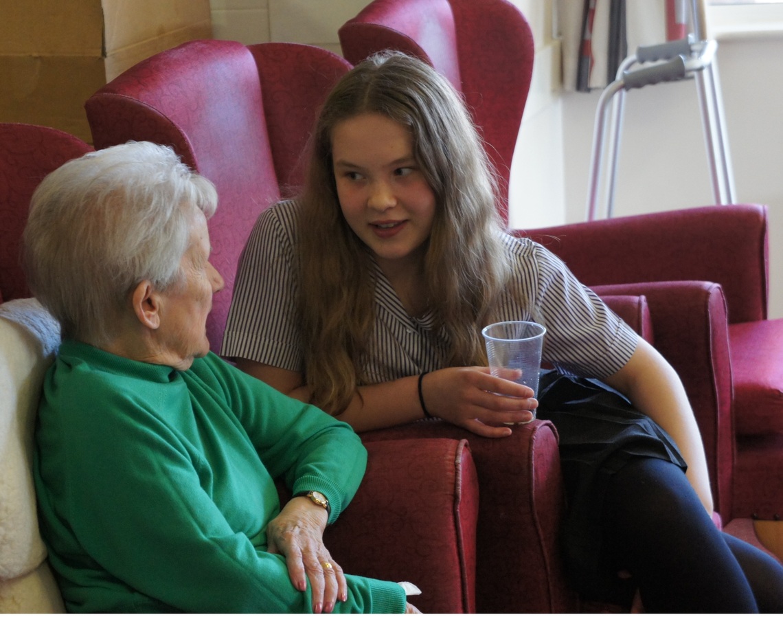 A young trumpeter talks to a care home resident