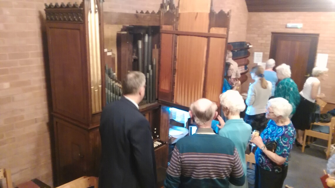 William McVicker delves inside the Chapel's chamber organ while other group members queue at the vestry bar